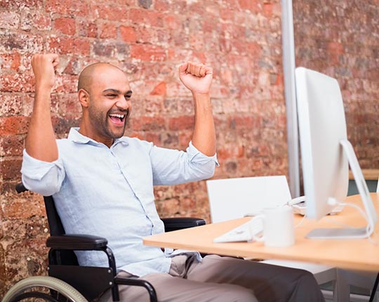 Happy man in wheelchair with a computer