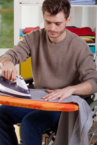 young man ironing clothes in a wheelchair